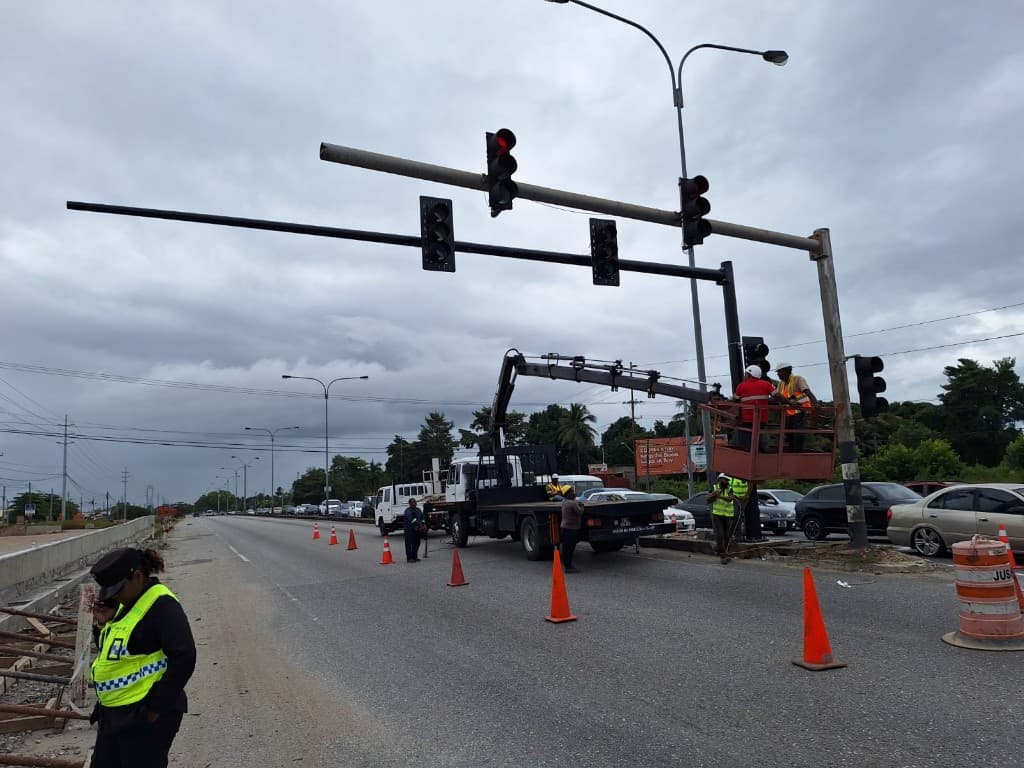 Team maintaining overhead traffic signals from a crane vehicle on a cordoned roadway
